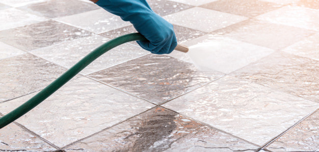 Worker power washing tiles in Denver Concrete Stain
